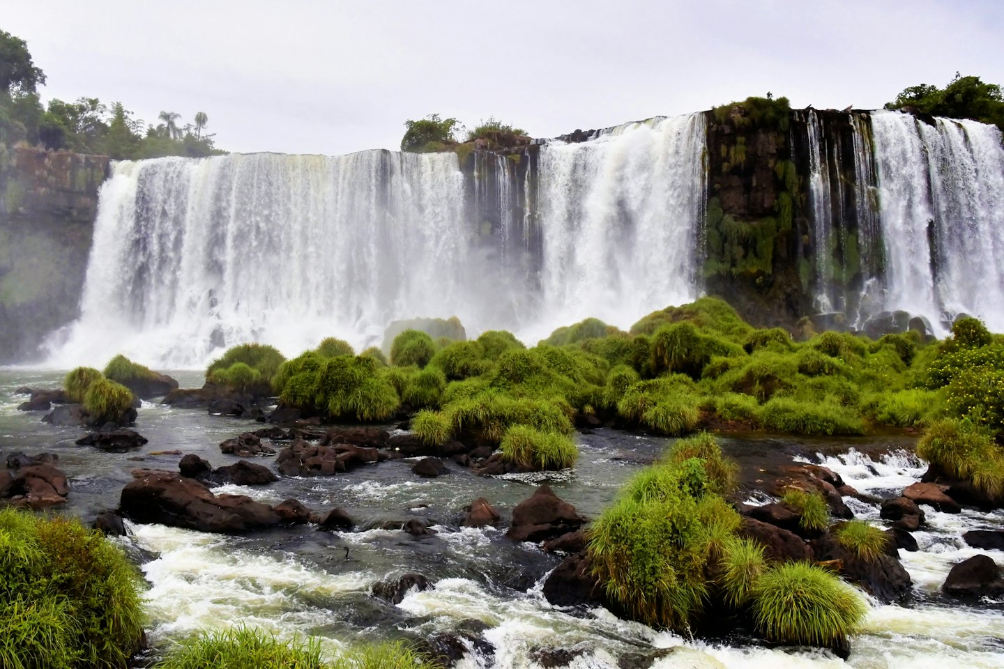 Water cascades over a rocky cliff into a river.