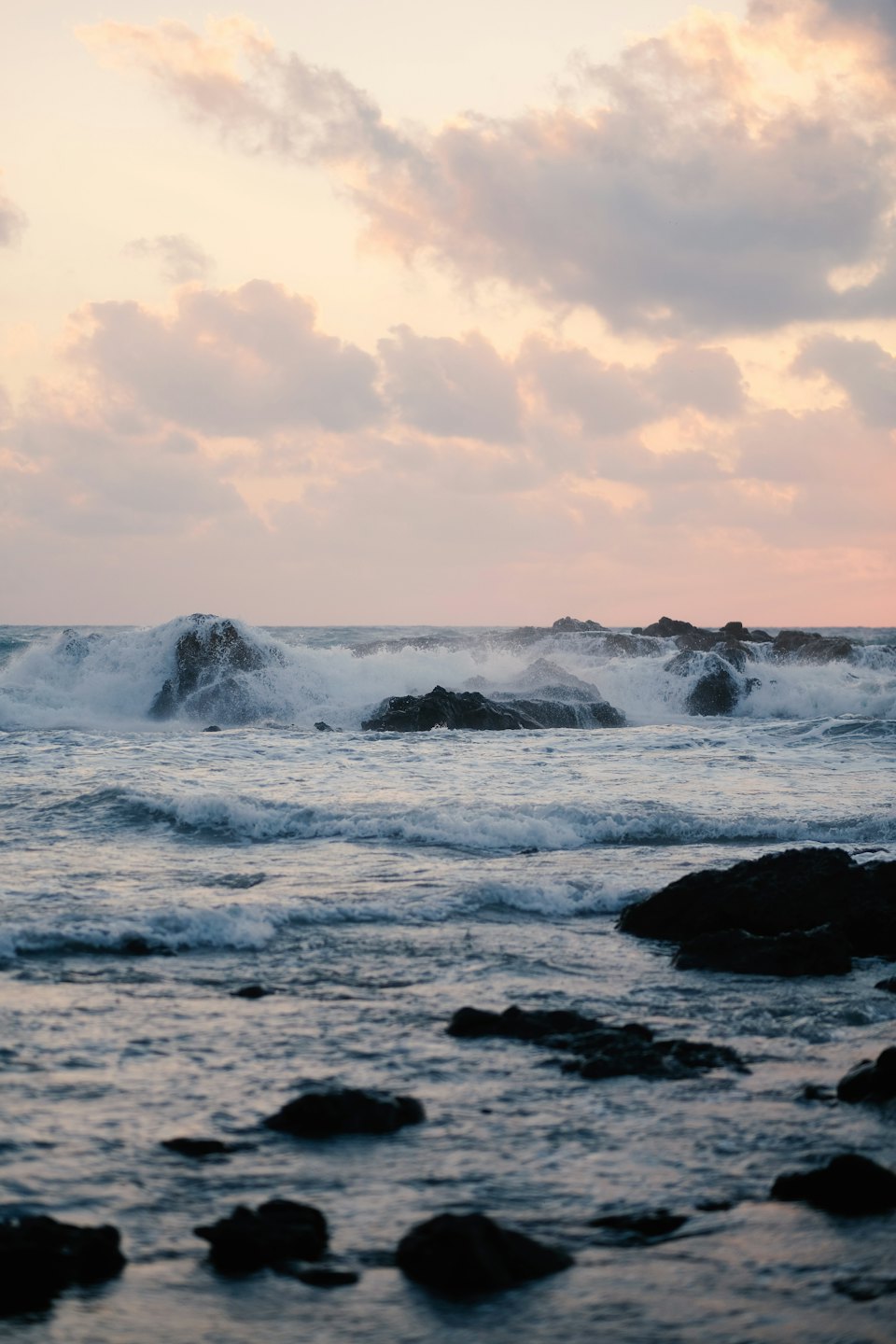 Ocean waves crash against dark jagged rocks along the coastline.