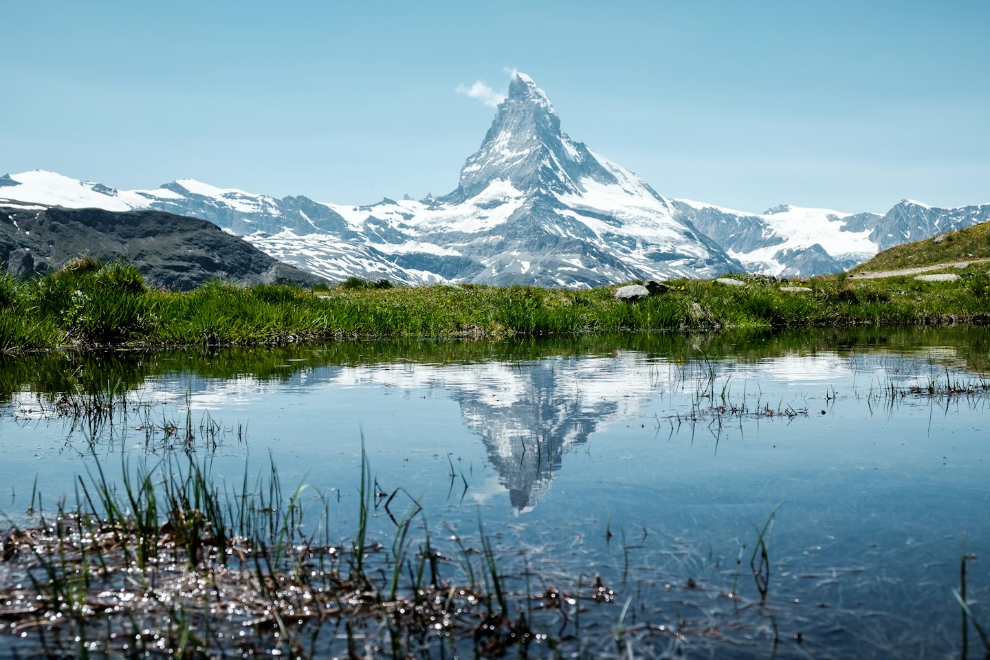 Snow-capped mountain peak reflected in a calm alpine lake.